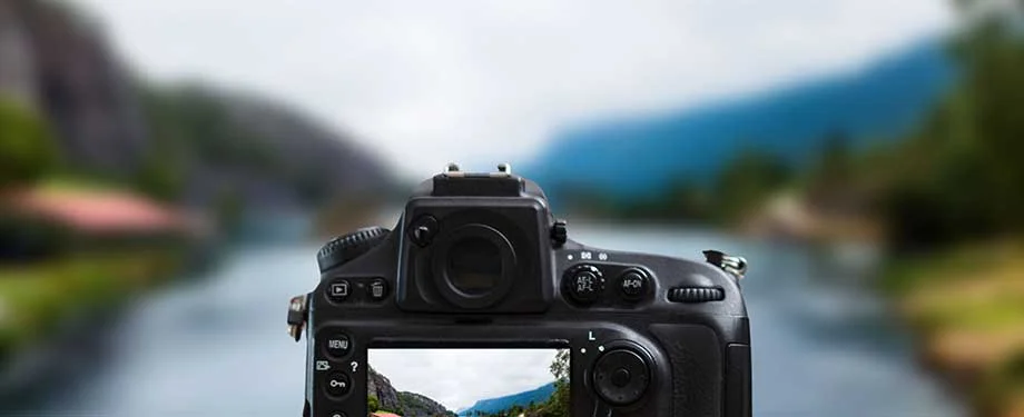 Câmera fotográfica profissional capturando paisagem com rio e montanhas representa o seguro para câmeras fotográficas