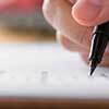 Mão segurando caneta e escrevendo representando contratação de seguro transporte com a corretora de seguros Mutuus